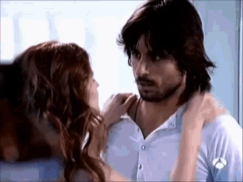 a man and a woman are kissing in a room . the woman is touching the man 's neck .