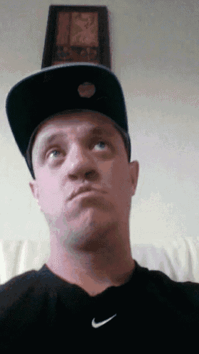 a man wearing a hat and a black nike shirt looks at the camera