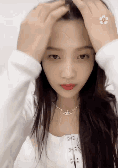 a woman wearing a white top and a necklace with a flower on her wrist .