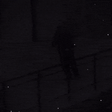 an elderly man is walking down a sidewalk next to a fence .