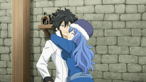 a boy and a girl are hugging each other in front of a brick wall