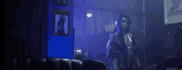 a woman is standing in a dark room with a picture on the wall .