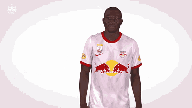 a man wearing a white red bull shirt waves his hand