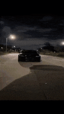 a black car is driving through a tunnel with a light coming out of it