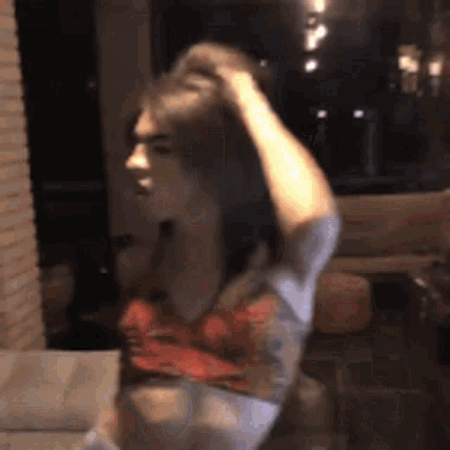 a woman in a crop top is holding her hair in a living room