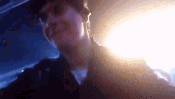 a blurry picture of a man in a dark room with a light behind him