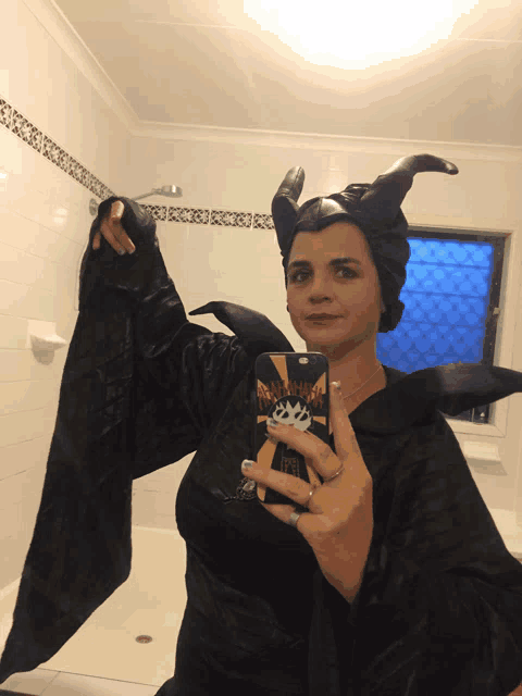 a woman in a maleficent costume is taking a picture of herself