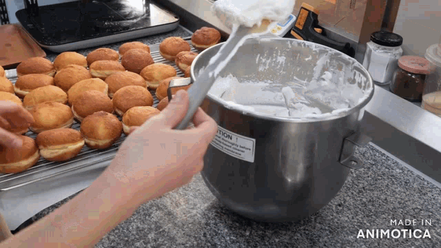 a person is mixing something in a metal bowl with a caution sign on it