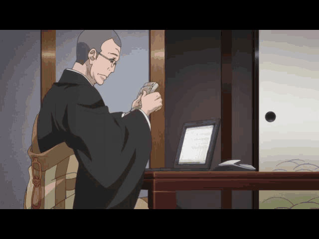 a man in a kimono sits at a table holding a piece of paper