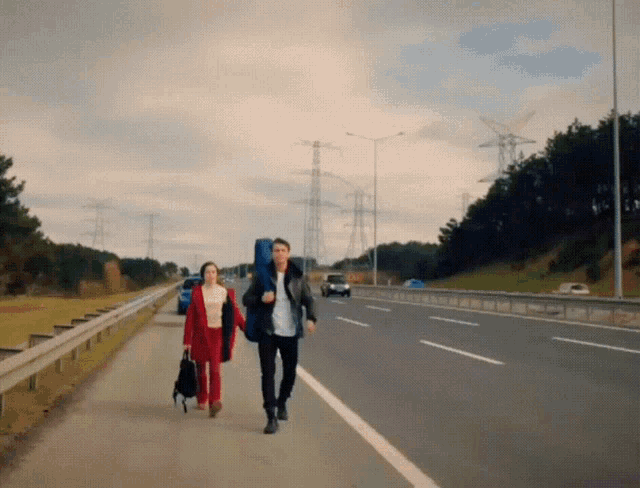 a man and a woman are walking down a road