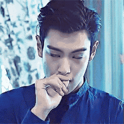 a man in a blue shirt covering his mouth with his hand