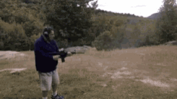 a man is standing in a field holding a rifle .