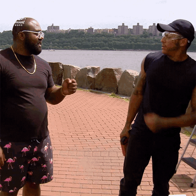 a man wearing flamingo shorts is standing next to another man