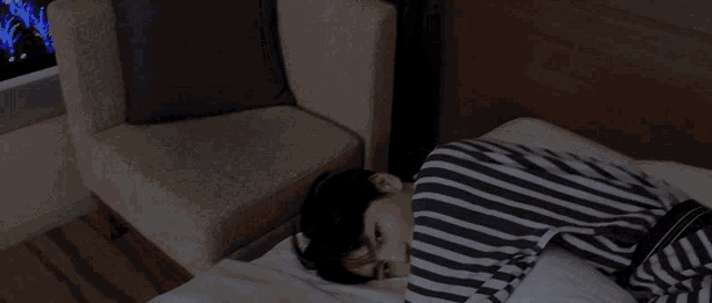 a person in a striped shirt is laying on a bed