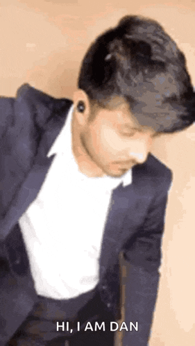 a man in a suit and white shirt is bending over and says hi , i am dan .