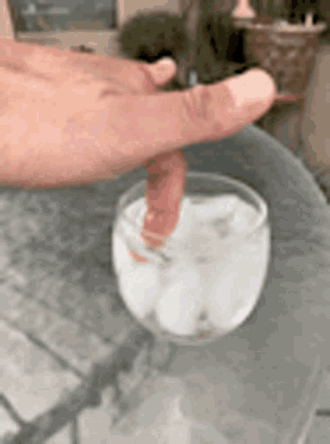 a person is holding a glass of water with ice cubes .