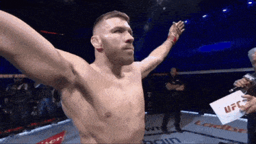 a man in a boxing ring with a microphone and a sign that says ufc on it