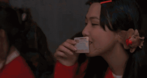 a man is holding a piece of paper in his mouth in front of a woman .