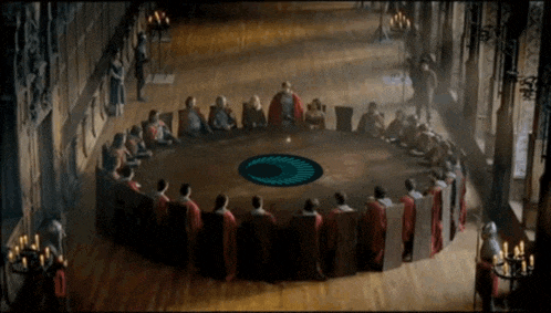 a group of people sit around a round table with a blue circle in the center