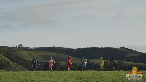 a group of power rangers running in front of a huge explosion