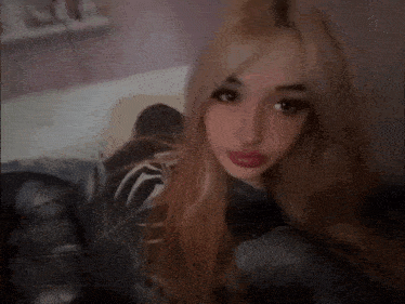 a girl with long blonde hair is wearing a spiderman costume and taking a selfie .