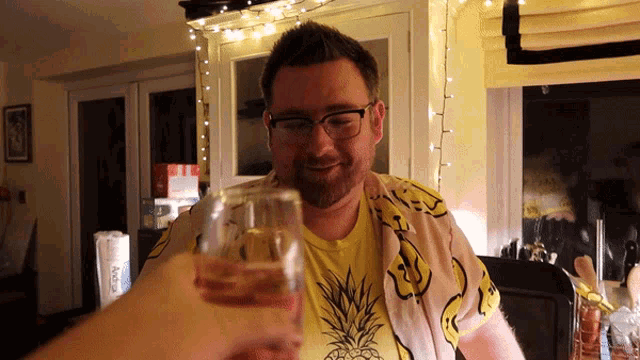a man wearing a yellow shirt with a pineapple on it is toasting