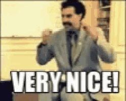 a man in a suit and tie is giving a thumbs up and saying `` very nice '' .