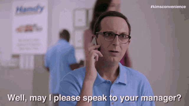 a man wearing glasses is talking on a cell phone and says " well may i please speak to your manager "