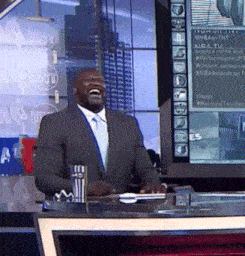 a man in a suit and tie is laughing in front of a sign that says nba