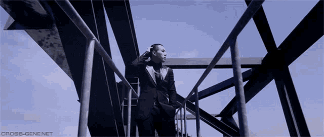 a man in a suit is standing on a bridge with the website cross-gene.net written below him