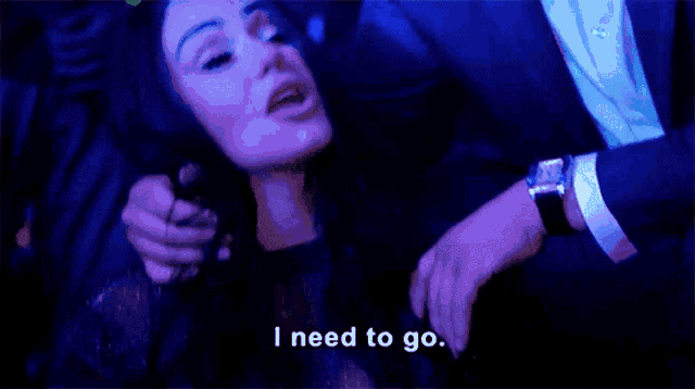 a man in a suit is holding a woman in a dark room and says i need to go .