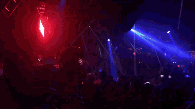 a crowd of people are dancing in a dark room with purple lights