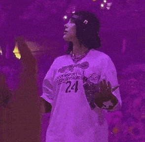 a woman is standing on a stage wearing a purple shirt .