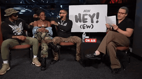 a group of people sit in front of a sign that says hey ( ew )