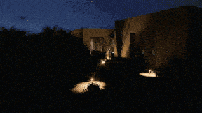 a house is lit up at night with a car parked in front of it