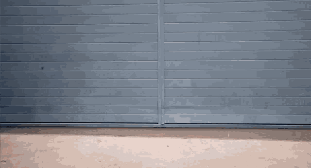 a blue garage door is open and a concrete floor is below it