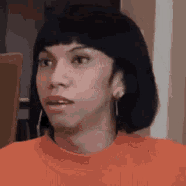 a close up of a person 's face with short hair and earrings .