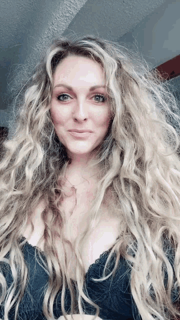 a woman with long blonde hair is wearing a black lace bra