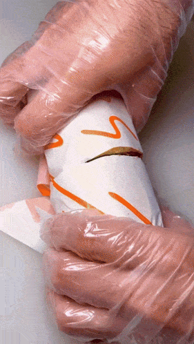 a person wearing plastic gloves holds a piece of paper with a s on it