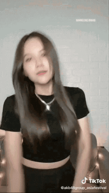 a woman in a black crop top is dancing in a tiktok video