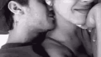 a man with a cross tattoo on his neck is kissing a woman on the neck .