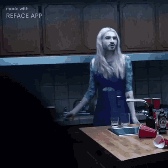 a woman in a blue dress is standing in a kitchen with a reface app logo