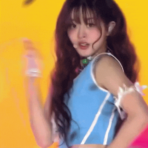 a woman in a blue top is dancing on a yellow background