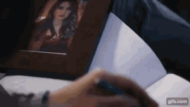 a person is writing in a notebook while looking at a picture of a woman on a tablet .