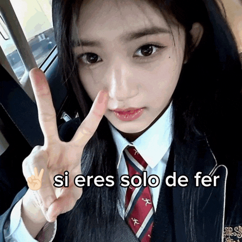 a girl in a school uniform giving a peace sign