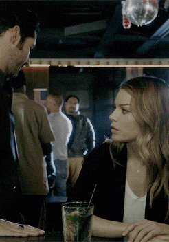 a man and a woman sitting at a bar with a drink in front of them
