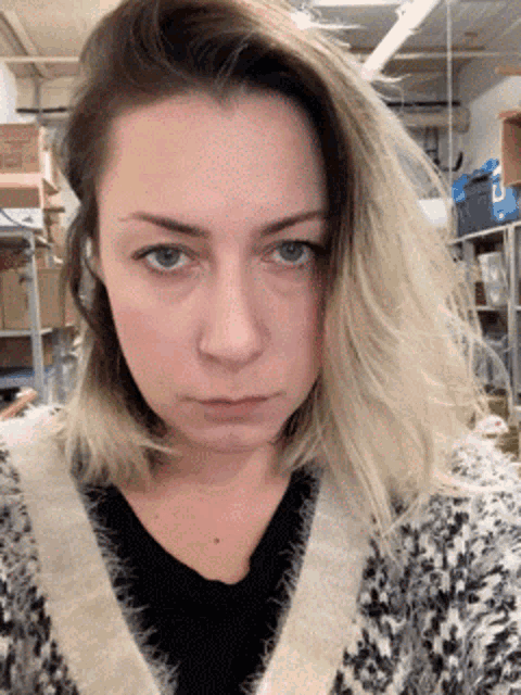 a woman wearing a black and white sweater is looking at the camera