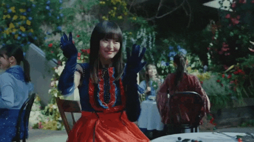 a woman in a red dress is sitting at a table with her arms crossed .