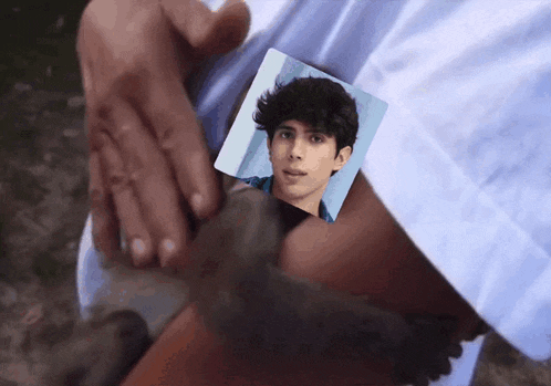 a person holds a picture of a young man in their hand
