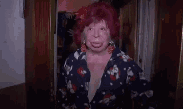 a woman with red hair and earrings is making a funny face while standing in a doorway .